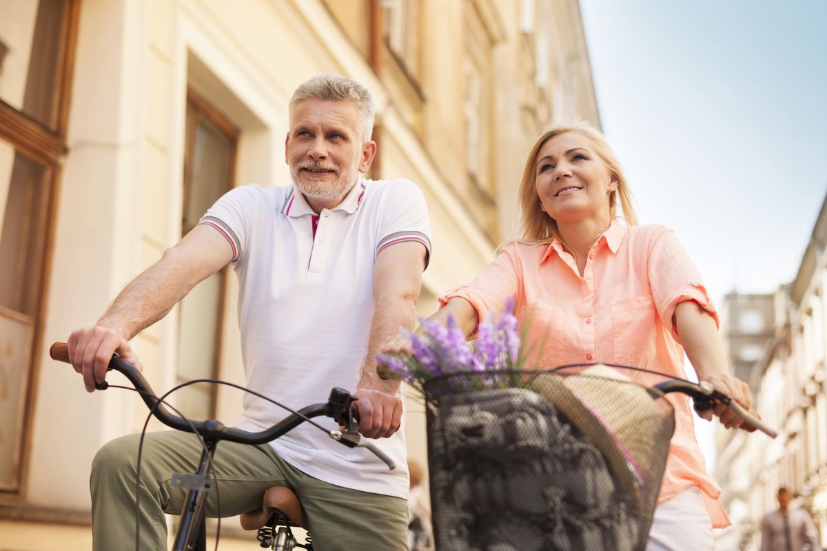 An elderly couple rides bikes together